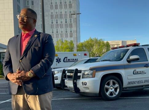 Augusta Mayor Garnett Johnson stands next to three Central EMS vehicles at a Sunday news conference about the status of EMS in Augusta. Staff photo by Susan McCord