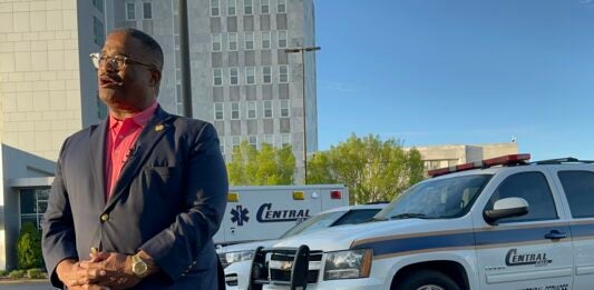 Augusta Mayor Garnett Johnson stands next to three Central EMS vehicles at a Sunday news conference about the status of EMS in Augusta. Staff photo by Susan McCord