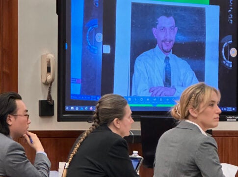 Sandra Dales, center, sits with her attorneys Jay Kim, left, and Jennifer Cross, right. Dales is on trial for murder in the death of her husband, Edward Cruey, whose photo is projected above her. In opening statements Wednesday, Cross portrayed Dales as a victim of domestic violence who killed Cruey in self defense. Staff photo by Susan McCord