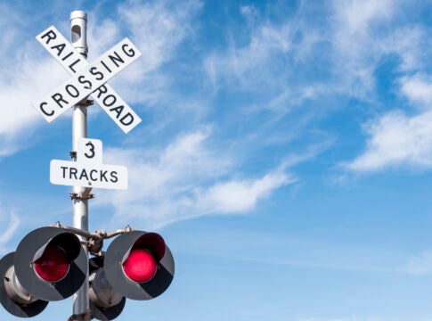 Railroad Crossing with Wispy Cloud in Blue Sky behind