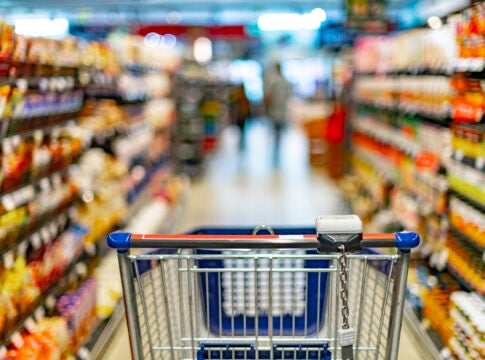 A shopping cart by a store shelf in a supermarket