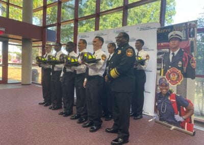 Fire Chief Antonio Burden poses for photos with the 13 new firefighters, of the graduating Recruit Class of 24-03. Photo by Skyler Andrews.