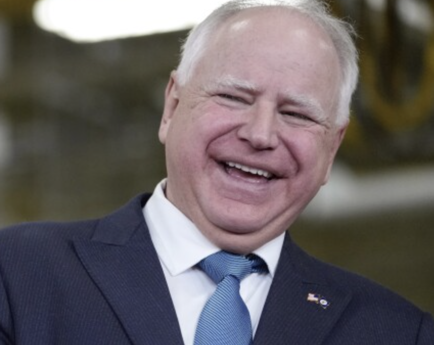 FILE - Minnesota Gov. Tim Walz laughs as he stands with Fridley, Minn., Mayor Scott Lund during a visit to the Cummins Power Generation Facility in Fridley, Minn., Monday, April 3, 2023. (AP Photo/Carolyn Kaster, File)