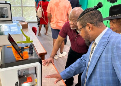 Morris Porter, foreground, chairman of the Augusta-Richmond County Library System board, shows visitors one of the system's new 3D printers. Susan McCord/staff