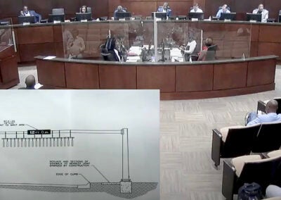 Top from left, commissioners Wayne Guilfoyle, Catherine Smith McKnight and Francine Scott, Mayor Garnett Johnson, Mayor Pro Tem Brandon Garrett and commissioners Sean Frantom and Alvin Mason look at a diagram of a device intended to discourage tall vehicles from attempting to drive under the low-clearance railroad bridge at Olive Road. Moments earlier, Lewis and Scott joined three other colleagues in skipping a called meeting to block Johnson’s effort to force a vote to hire Tameka Allen as new city administrator. Staff photo by Susan McCord