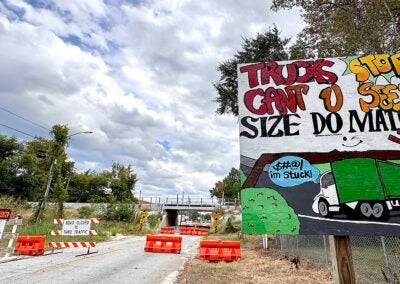 The frequently-struck CSX underpass at Olive Road, reportedly designated by some 30 Augusta traffic devices, included a mishmash of concrete and rubber barricades, traffic signs and this handpainted warning Tuesday. The bridge is expected to be open to vehicle traffic Wednesday after an Augusta Commission vote. Staff photo by Susan McCord