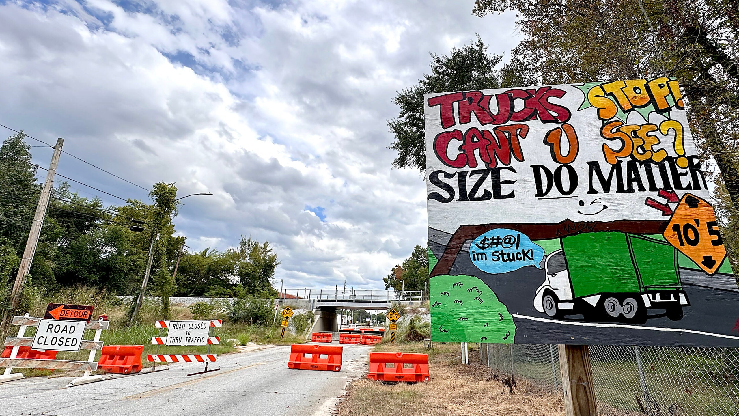 The frequently-struck CSX underpass at Olive Road, reportedly designated by some 30 Augusta traffic devices, included a mishmash of concrete and rubber barricades, traffic signs and this handpainted warning Tuesday. The bridge is expected to be open to vehicle traffic Wednesday after an Augusta Commission vote. Staff photo by Susan McCord