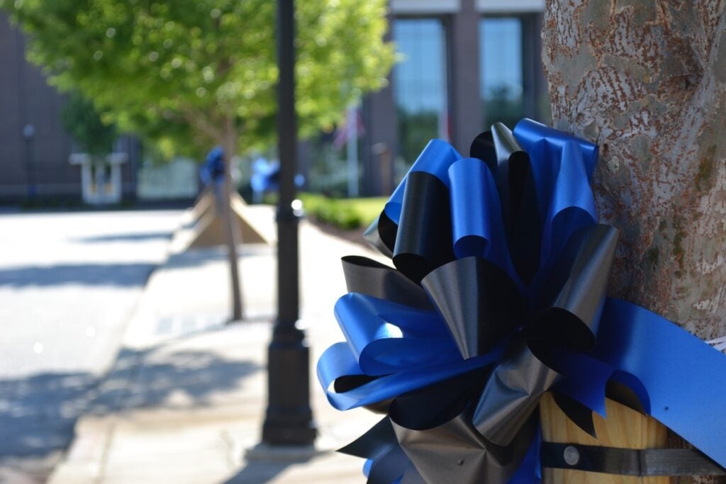 Blue and black ribbons were tied around trees at the Columbia County Performing Arts Center ahead of the funeral for Deputy Brandon Sikes. Staff photo by Stephanie Hill