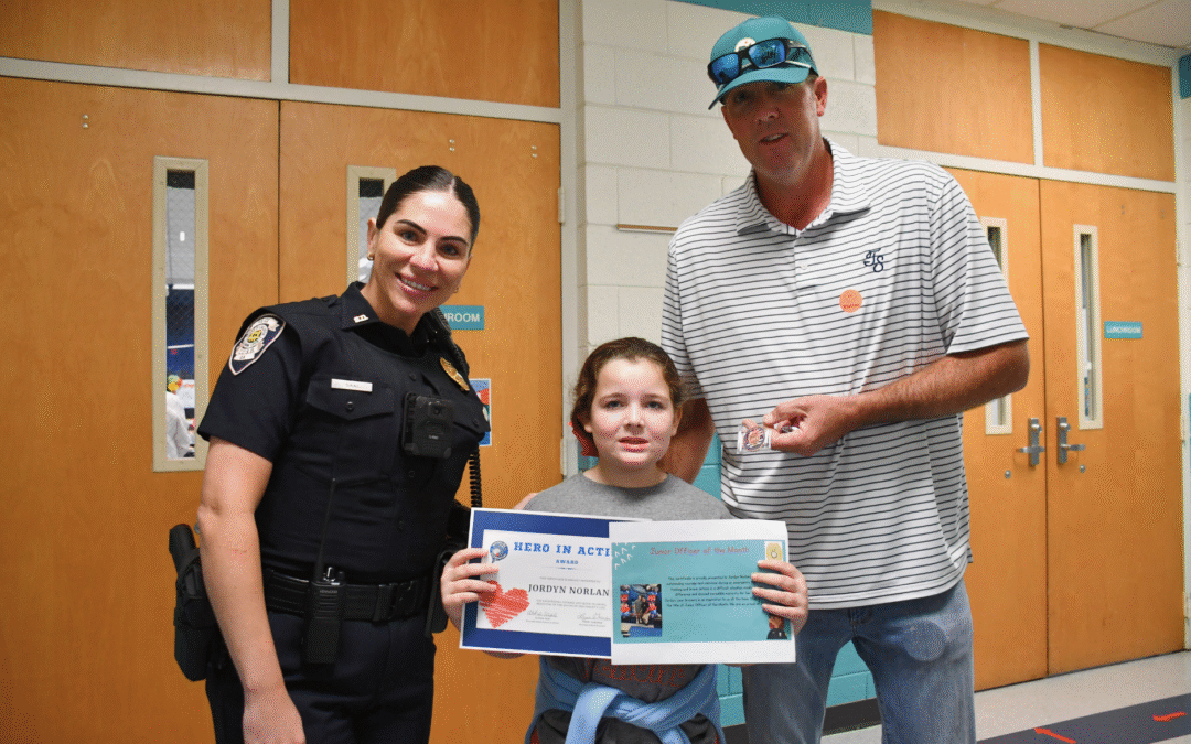 Riverside Elementary second grader Jordyn Norland is pictured with Officer Saal and her father, Mike, after being honored during the school’s Student of the Month event for calling 911 and helping save her mother’s life. Photo courtesy Columbia County School District