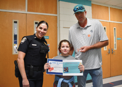 Riverside Elementary second grader Jordyn Norland is pictured with Officer Saal and her father, Mike, after being honored during the school’s Student of the Month event for calling 911 and helping save her mother’s life. Photo courtesy Columbia County School District