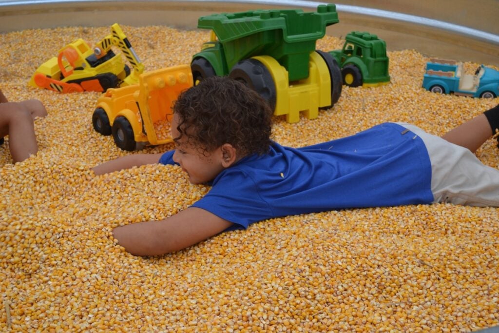 Jordan Quinones, 5, had a fun time burying himself in the corn kernel pit at Good Earth. Staff photo by Stephanie Hill