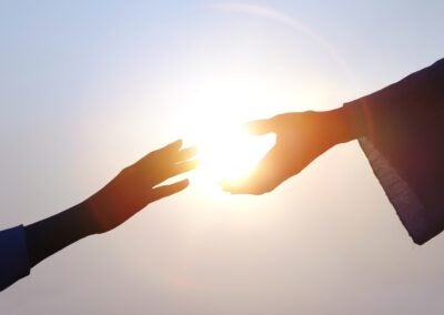 Hand of salvation, Christian hand reaching out to the hand of Jesus Christ, bright sun silhouette