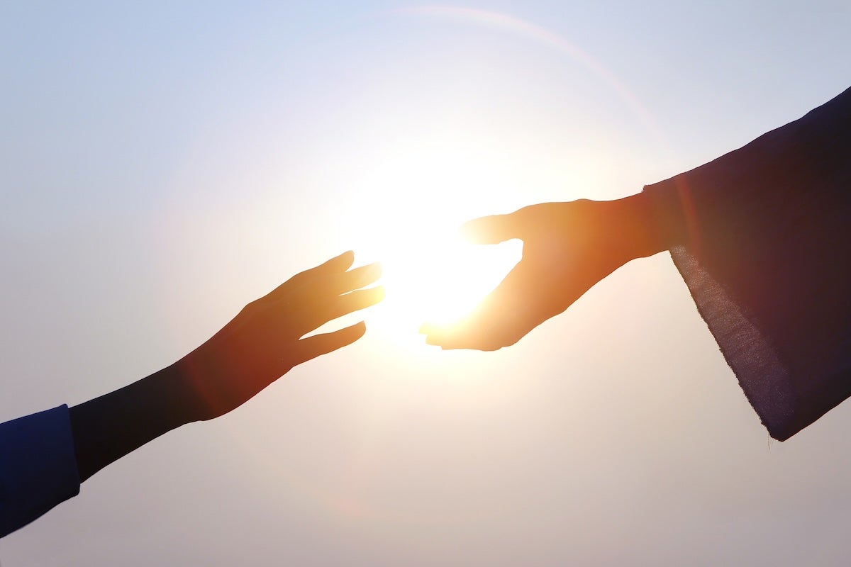 Hand of salvation, Christian hand reaching out to the hand of Jesus Christ, bright sun silhouette Hand of salvation, Christian hand reaching out to the hand of Jesus Christ, bright sun silhouette